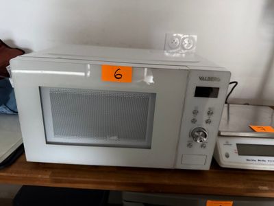 un micro-ondes posé sur une table à côté d'une horloge
