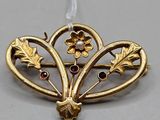 a close up of a gold brooch with flowers and leaves