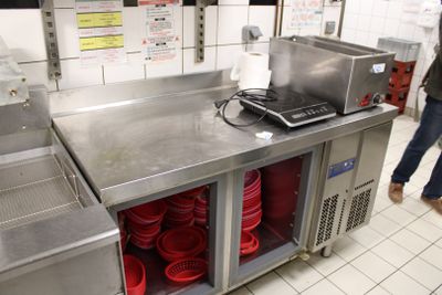 un homme debout dans une cuisine, avec beaucoup de vaisselle sur le plan de travail