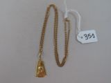 une image représentant un collier en or auquel est suspendue une clochette