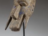 a close up of a wooden mask on a metal stand