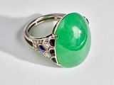 une image représentant une bague en jade vert et saphir posée sur une surface blanche