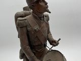 bronze statue of a man with a drum and a hat