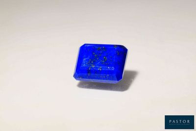 un gros plan d'une pierre bleue carrée posée sur une surface blanche