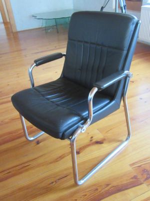 a black leather chair sitting on a hard wood floor