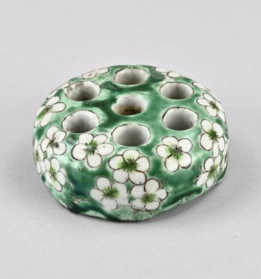 une photo d'un vase vert et blanc orné de fleurs