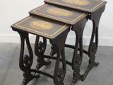 trois tables gigognes anciennes, noires et dorées, posées sur un sol gris