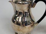 a silver tea pot with a black handle on a white table