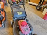 Plusieurs tondeuses à gazon sont alignées dans un garage