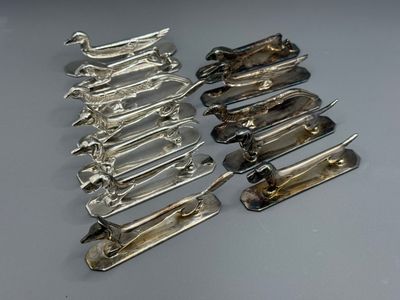 six pairs of silver plated scissors are lined up on a table