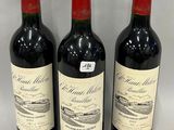 three bottles of red wine are lined up on a table