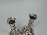 two silver candlesticks sitting on a white table