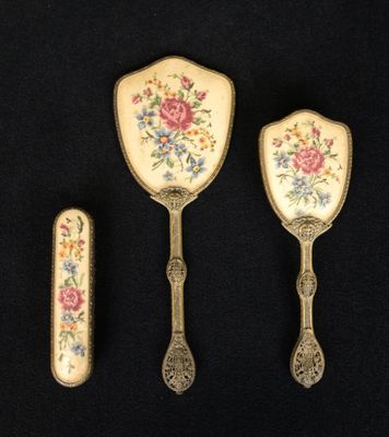 three pieces of silverware with floral designs on them on a black surface