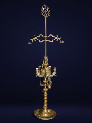 a gold plated cross on a stand with three candles