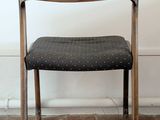 a wooden chair with a black seat on a brick floor