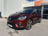 une voiture rouge garée devant un immeuble, sur un parking