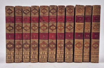 six old books are lined up in a row on a white surface