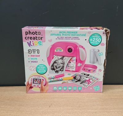 Quelqu'un prend une photo d'un appareil photo rose posé sur une table.