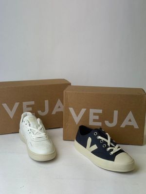 pair of white and blue sneakers sitting next to a box of vejaa shoes