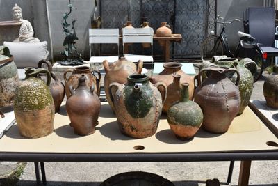 many vases sitting on a table in a yard