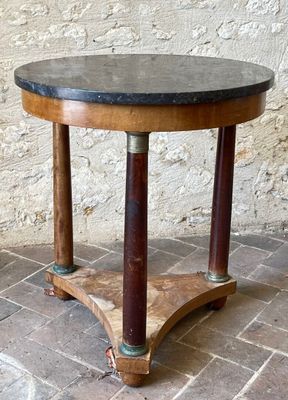 a small table with a marble top on a brick floor