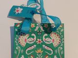 un sac cadeau vert orné d'un ruban bleu noué autour