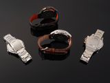 three watches and a watch band on a black surface