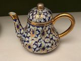 a blue and gold teapot sitting on a table