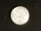 a silver coin on a black surface with a black background