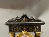 a black and gold clock on a stand on a table