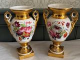 two vases are sitting on a table with a wallpaper behind them