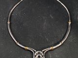a silver necklace with a celtic knot on a black surface