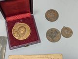 a gold medal sitting next to a book and some coins