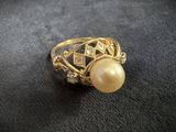 a close up of a gold ring with a pearl and diamonds