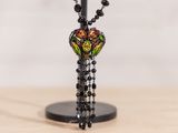 collier de perles noires avec une perle en verre multicolore et un pompon