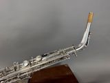 an image of a silver saxophone on a wooden stand on a gray background