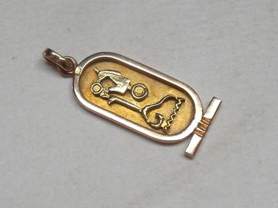 a gold pendant with a picture of a horse and carriage on it