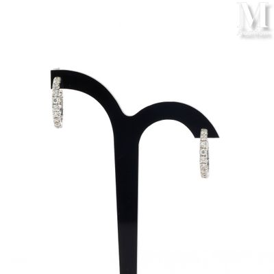 pair of diamond hoop earrings on a black stand on a white background
