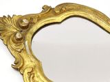 a mirror with a gold frame on a white surface