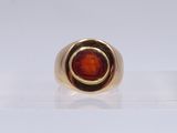 gros plan d'une bague en or avec une pierre rouge au centre