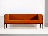 an orange couch sitting on top of a white platform next to a wall