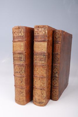 two old books sitting on top of each other on a white surface