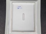 a small square white plate with a blue sticker on it