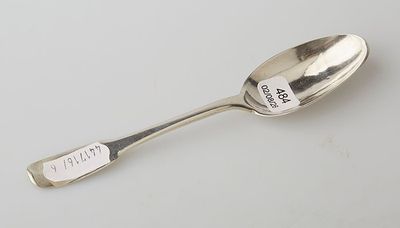 silver spoon with writing on it sitting on a white surface