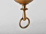 a brass bell hanging from a hook on a wall