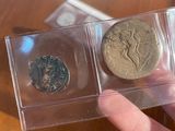 a person holding two coins in a clear box on a table