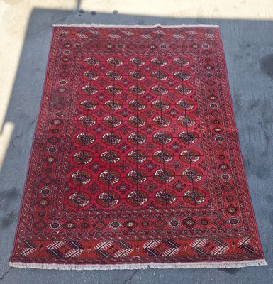 Un tapis oriental est posé par terre, au soleil.