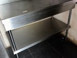 a stainless steel table with a shelf underneath it in a kitchen