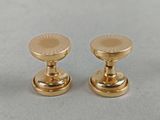 pair of gold plated brass door knobs on a gray surface
