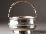 a small silver bowl with a handle on a table